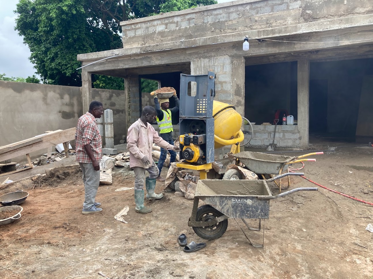 Building construction site supervision in Accra, Ghana — workers with cement mixer during multi-storey concrete frame construction
