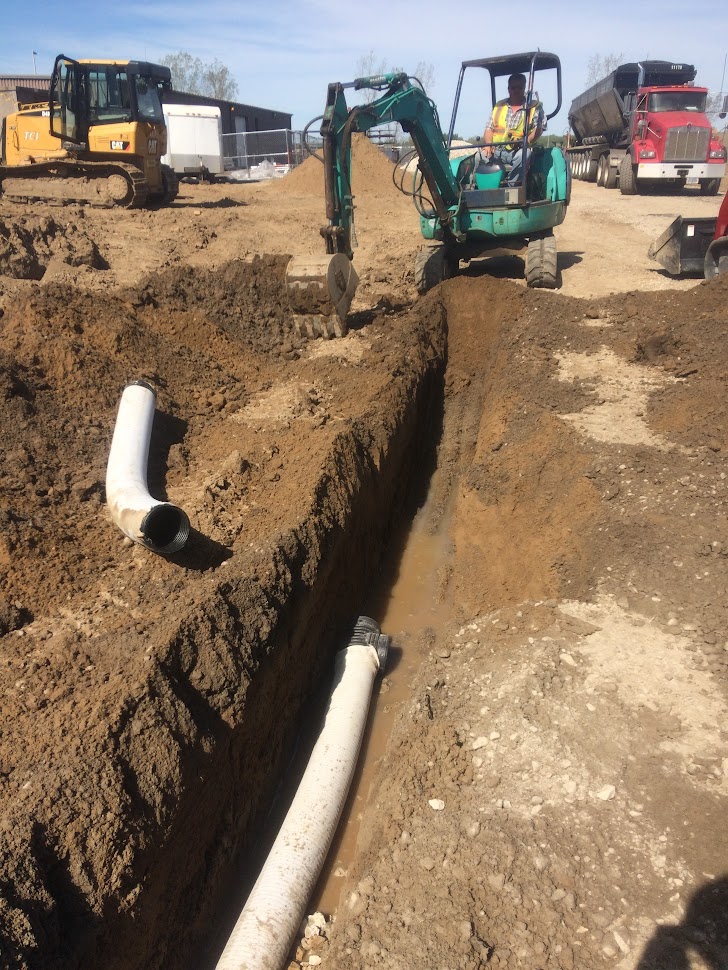 Mini-excavator and stormwater pipe in excavated trench — civil drainage works and stormwater infrastructure