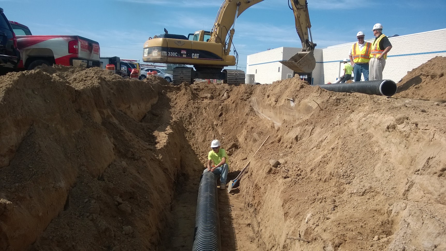 Workers installing large corrugated stormwater drainage pipe in excavated trench — flood control and drainage engineering project